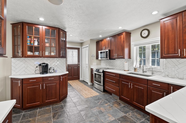 kitchen with stainless steel appliances, a sink, healthy amount of natural light, recessed lighting, and backsplash