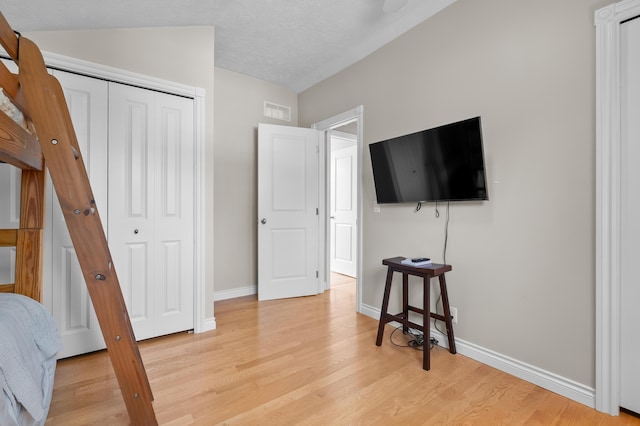 bedroom featuring light wood-style flooring, baseboards, and a closet