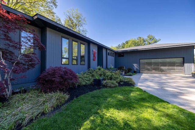 view of front facade featuring an attached garage, concrete driveway, and a front lawn