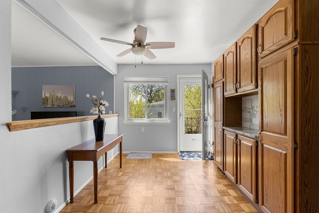 doorway with baseboards and ceiling fan