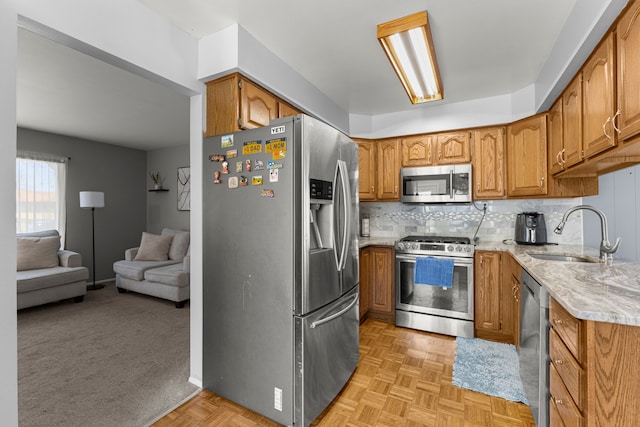 kitchen with stainless steel appliances, brown cabinets, a sink, and open floor plan