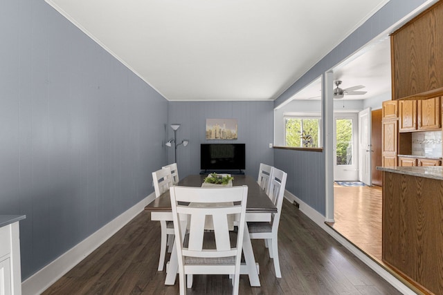 dining space featuring dark wood-style flooring, ceiling fan, baseboards, and crown molding