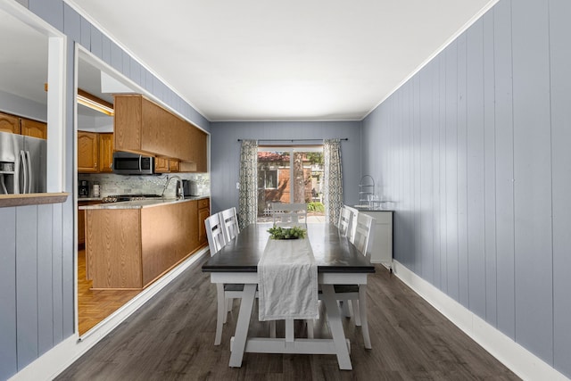 dining space featuring dark wood finished floors, ornamental molding, and baseboards