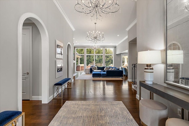 foyer entrance featuring a chandelier, crown molding, wood finished floors, baseboards, and arched walkways
