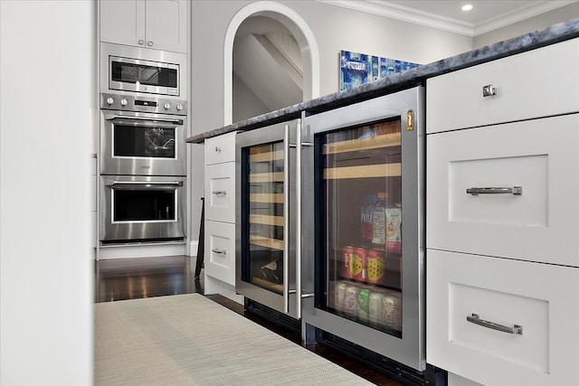 kitchen featuring appliances with stainless steel finishes, crown molding, wine cooler, white cabinets, and recessed lighting