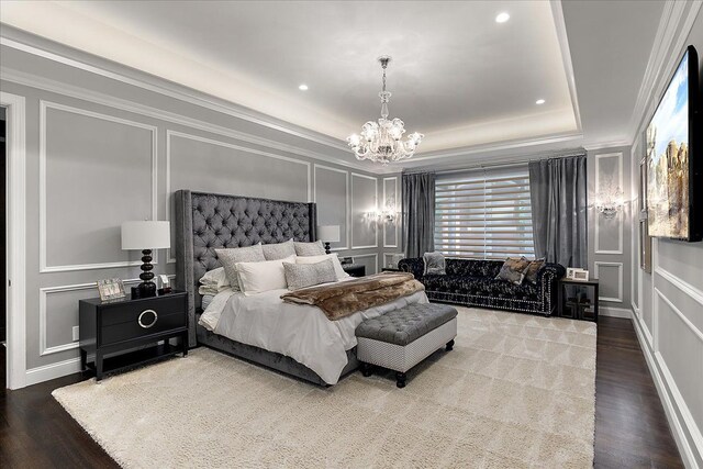 bedroom featuring a decorative wall, a chandelier, wood finished floors, a raised ceiling, and ornamental molding