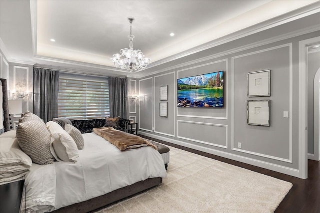 bedroom featuring a decorative wall, a chandelier, crown molding, wood finished floors, and a tray ceiling