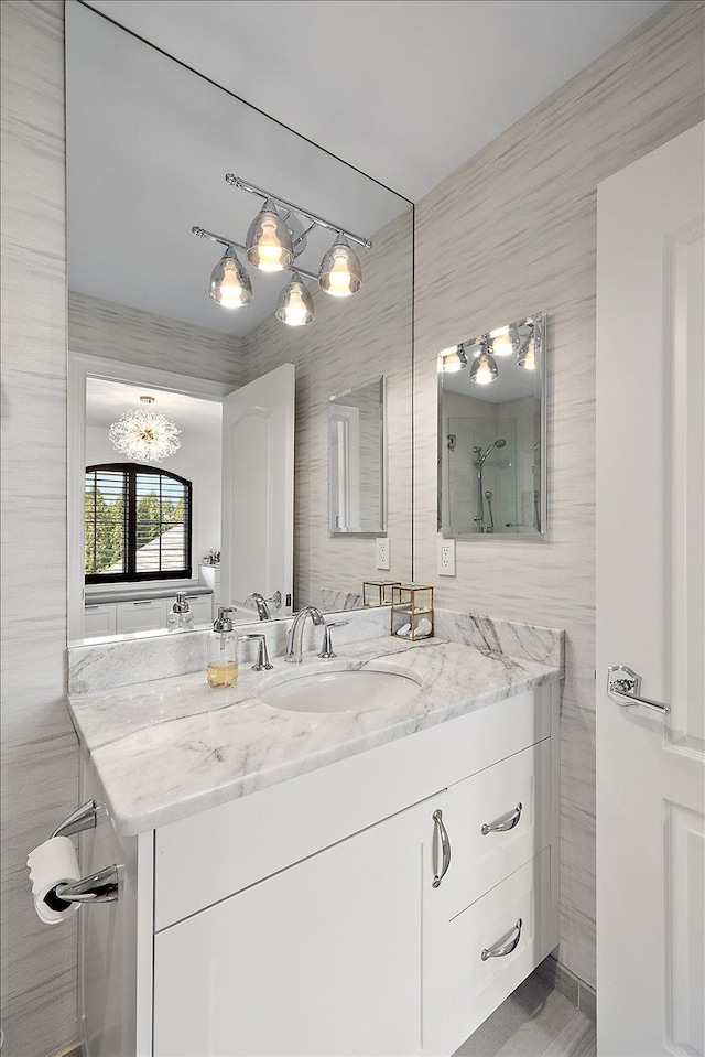 bathroom featuring vanity, tile walls, a shower, and a chandelier
