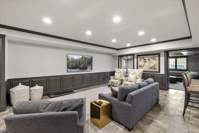 home theater room with a decorative wall, crown molding, a raised ceiling, recessed lighting, and a wainscoted wall