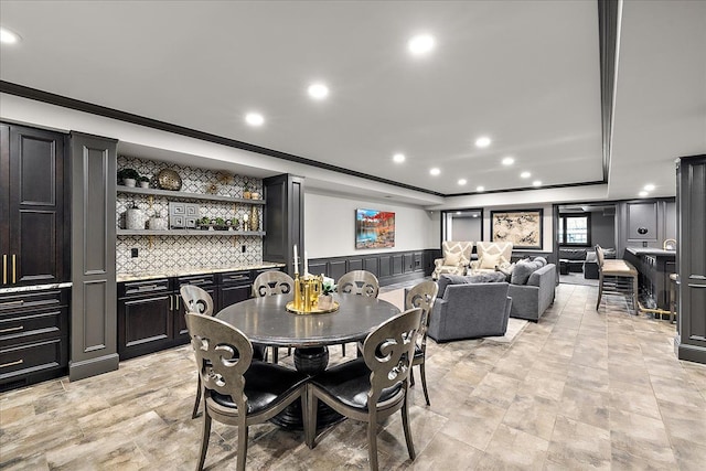 dining space with bar, a tray ceiling, recessed lighting, ornamental molding, and a decorative wall