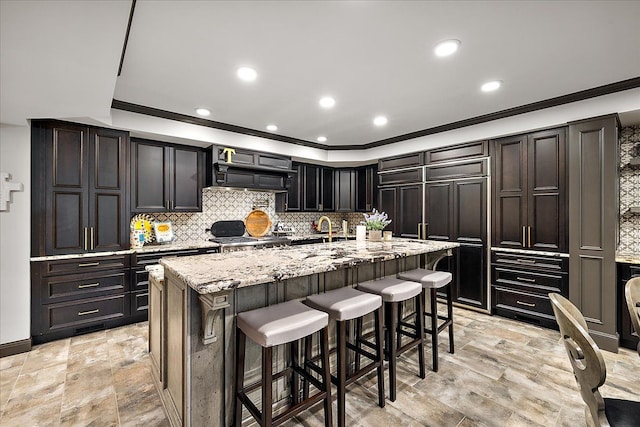 kitchen with crown molding, a breakfast bar, custom range hood, light stone countertops, and decorative backsplash