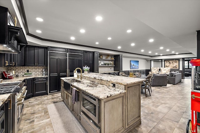 kitchen with stainless steel appliances, ornamental molding, a sink, backsplash, and light stone countertops