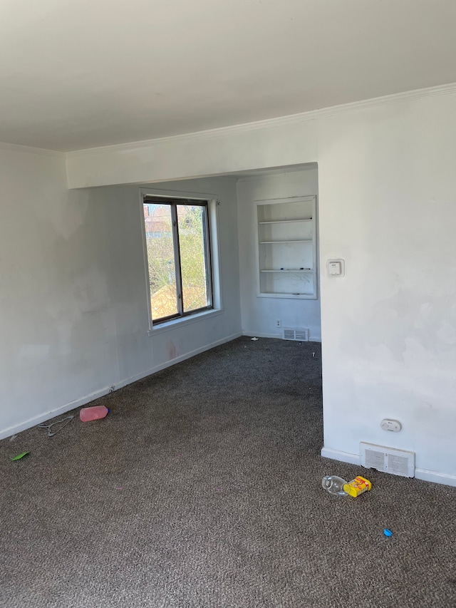 unfurnished room featuring dark colored carpet, ornamental molding, and baseboards