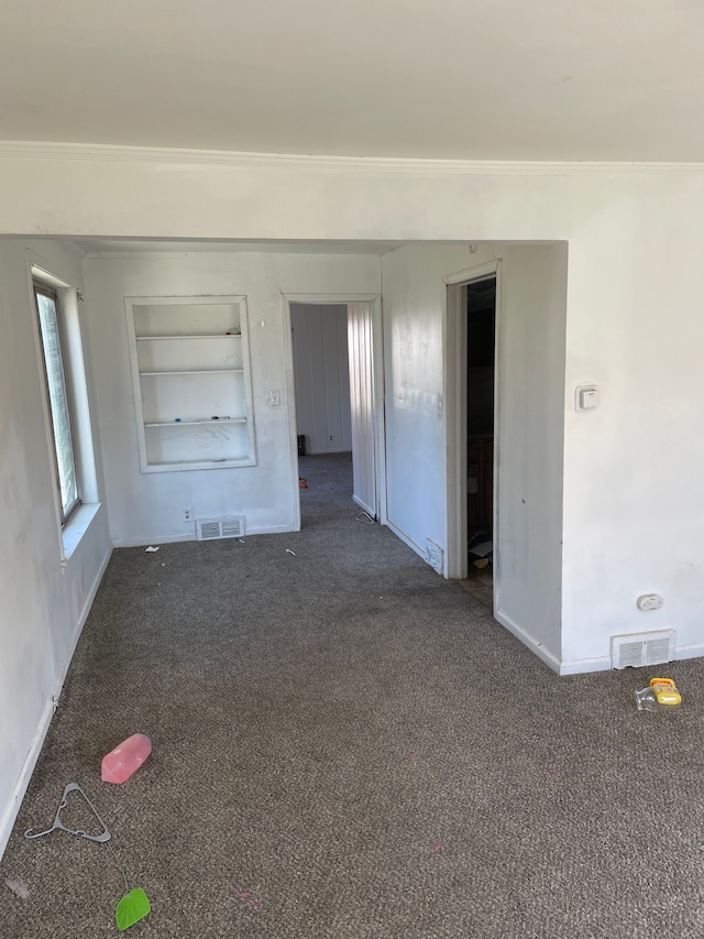 spare room with baseboards, built in features, carpet floors, and ornamental molding