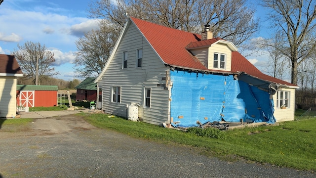 view of side of home with a chimney and an outbuilding