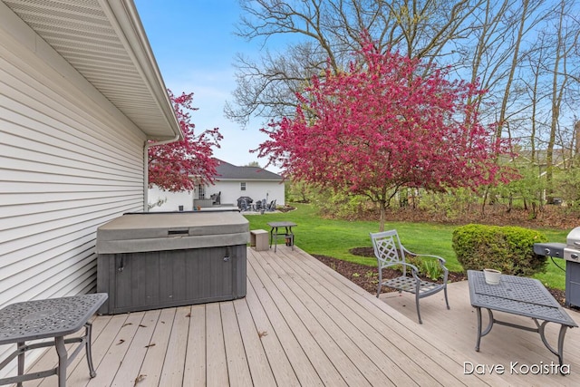 wooden deck featuring a hot tub and a lawn