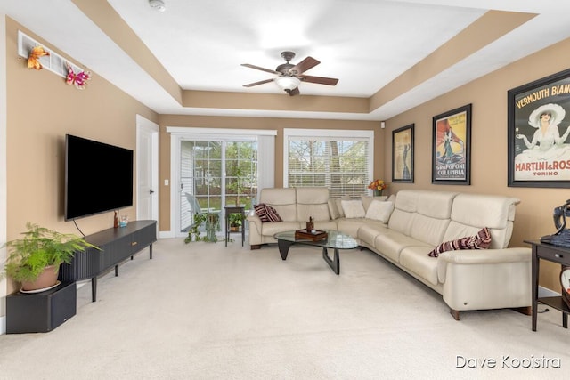 carpeted living area with ceiling fan and a tray ceiling