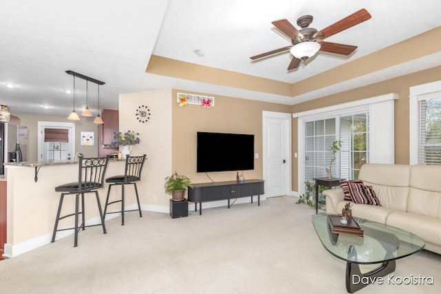 living room with light carpet, baseboards, and ceiling fan