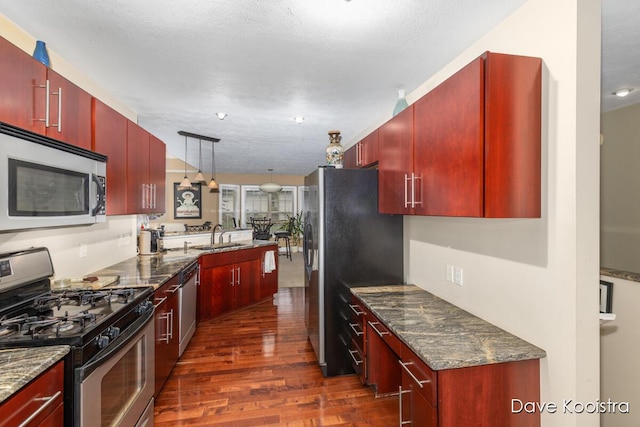kitchen with appliances with stainless steel finishes, dark wood-style flooring, dark brown cabinets, and a sink