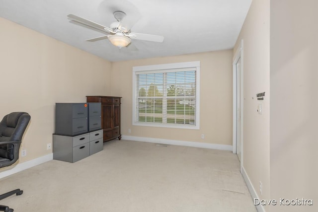 unfurnished office featuring light colored carpet, baseboards, and ceiling fan