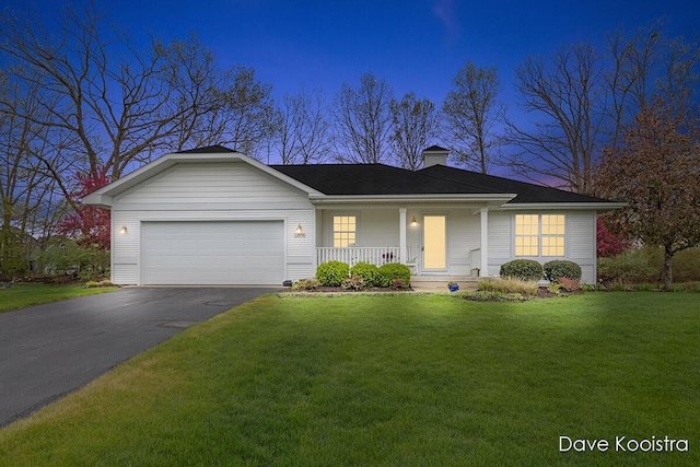 ranch-style house with covered porch, asphalt driveway, a garage, and a front yard