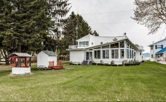back of property featuring a sunroom, a shed, an outbuilding, and a lawn