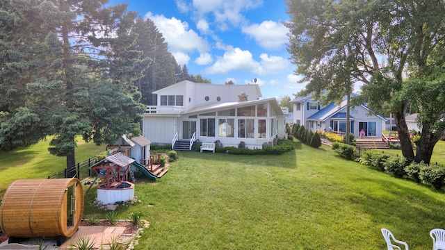rear view of house with a sunroom, a storage shed, a lawn, and an outdoor structure