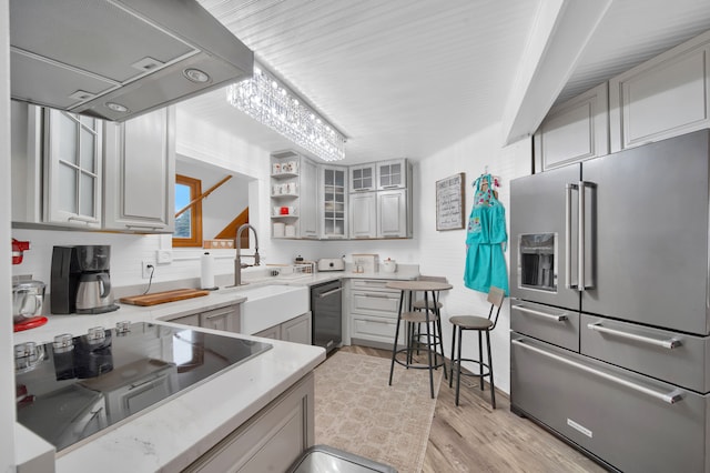 kitchen with high quality fridge, dishwasher, under cabinet range hood, gray cabinetry, and glass insert cabinets