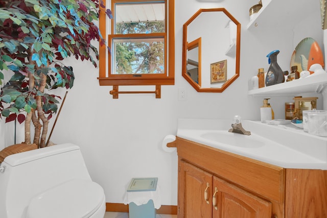 half bath with vanity, toilet, and baseboards