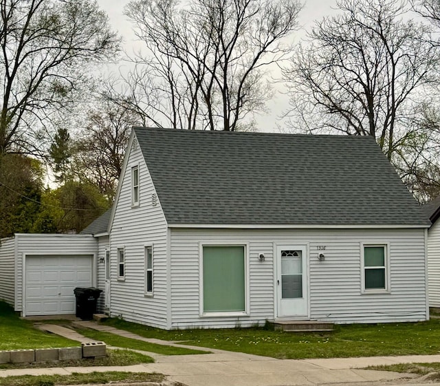 view of front facade with roof with shingles, a garage, and a front lawn