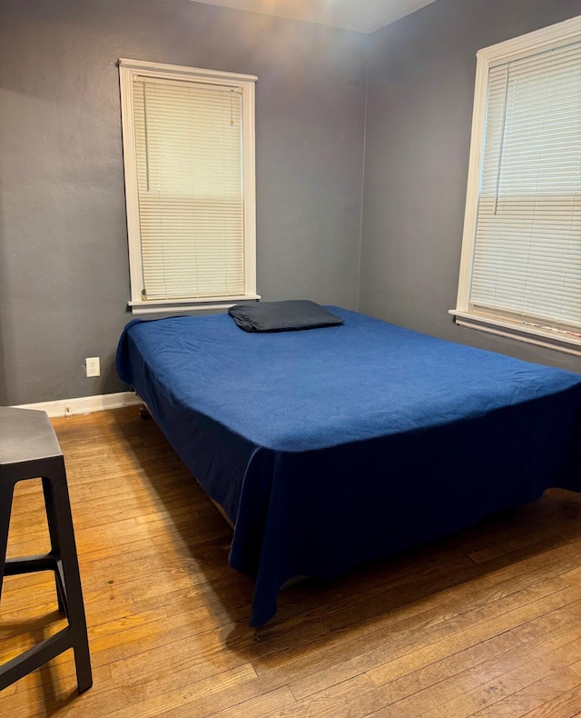 bedroom with hardwood / wood-style floors and baseboards