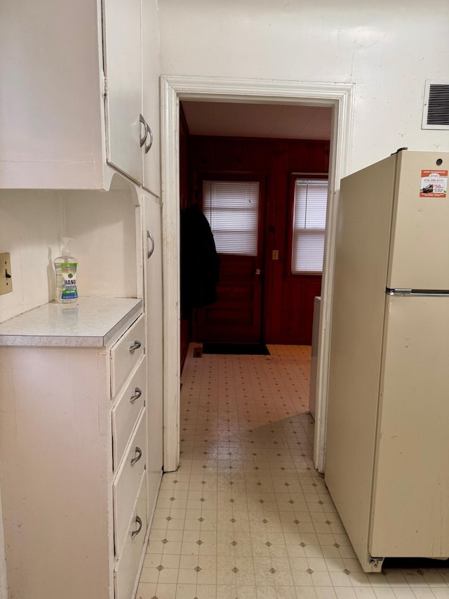 kitchen featuring freestanding refrigerator, light floors, white cabinets, and light countertops