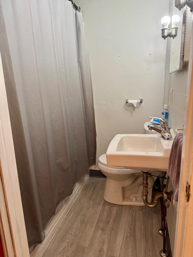 bathroom featuring wood finished floors, curtained shower, and toilet