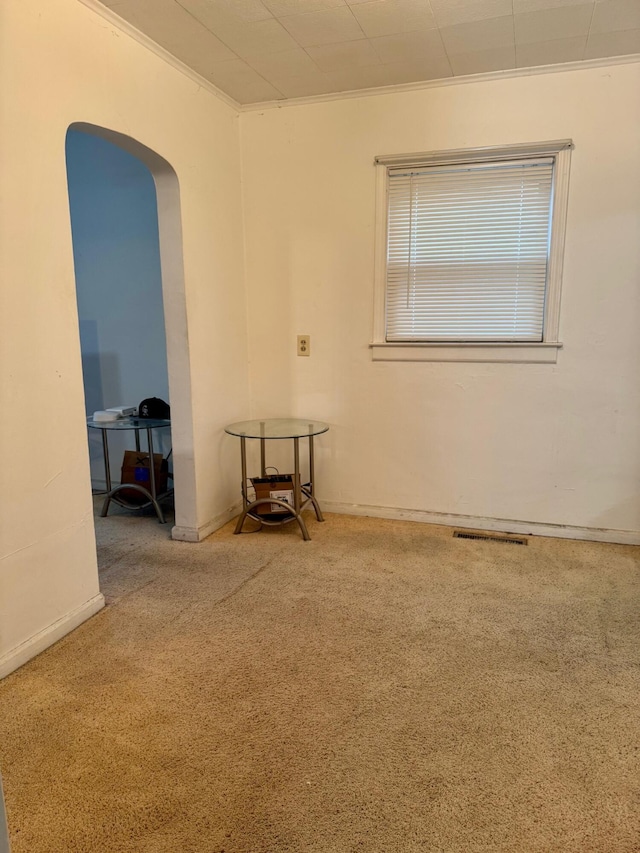 unfurnished room with carpet, arched walkways, and ornamental molding