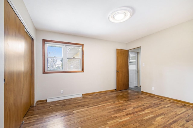 2228 Washington Ave, Saint Joseph, MI 49085 - unfurnished bedroom with a baseboard heating unit, light wood-style flooring, a closet, and baseboards
