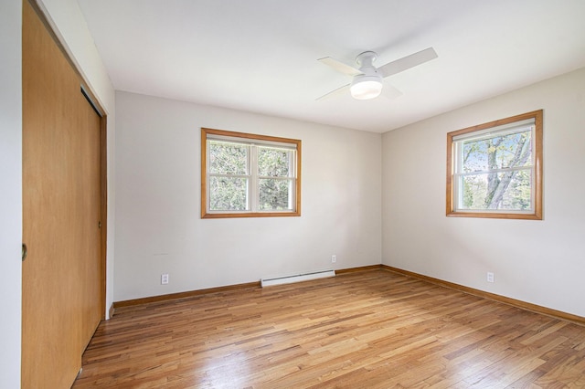 2228 Washington Ave, Saint Joseph, MI 49085 - unfurnished bedroom with a baseboard heating unit, multiple windows, light wood-style flooring, and a closet