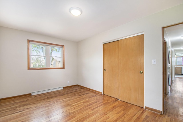 2228 Washington Ave, Saint Joseph, MI 49085 - unfurnished bedroom with baseboard heating, light wood-style floors, a closet, and baseboards