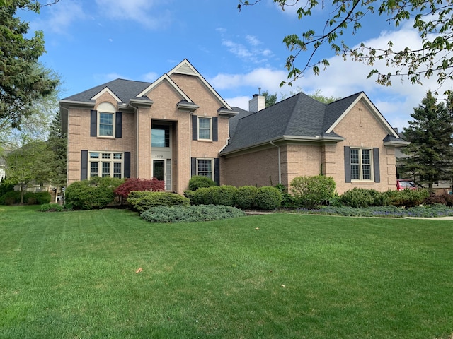 1079 Trailside Blvd, Wixom, MI 48393 - traditional-style home with brick siding, a front lawn, a chimney, and a shingled roof