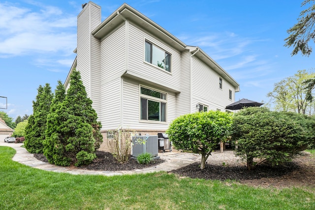 1079 Trailside Blvd, Wixom, MI 48393 - view of side of home with central AC, a chimney, and a yard