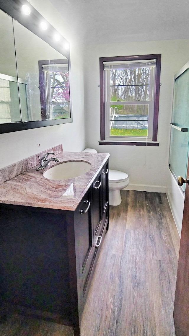 2127 E Coldwater Rd, Flint, MI 48505 - full bathroom with wood finished floors, vanity, toilet, baseboards, and enclosed tub / shower combo
