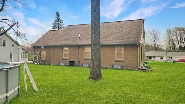 2127 E Coldwater Rd, Flint, MI 48505 - back of property featuring a lawn, brick siding, a shingled roof, and central AC unit