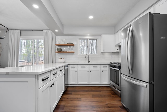 kitchen with appliances with stainless steel finishes, a peninsula, white cabinetry, decorative backsplash, and recessed lighting