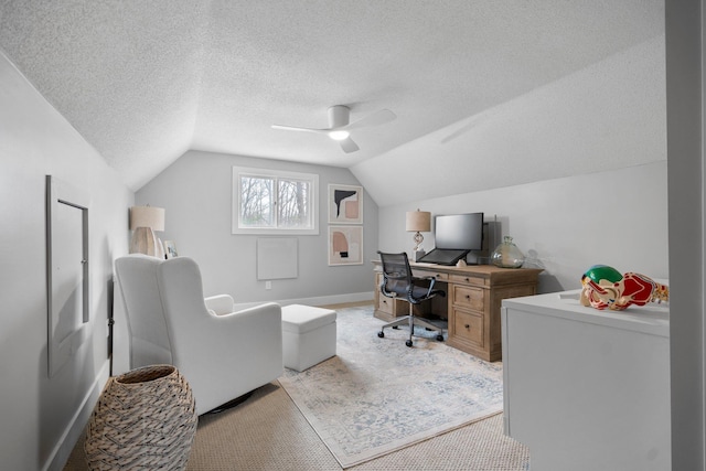 office featuring lofted ceiling, a textured ceiling, light colored carpet, a ceiling fan, and baseboards