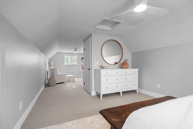 bedroom featuring light carpet, lofted ceiling, a ceiling fan, baseboards, and a textured ceiling