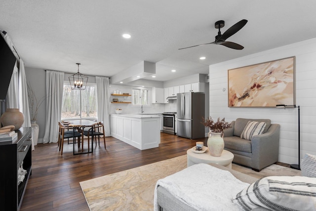 living room with a ceiling fan, dark wood-style floors, a chandelier, recessed lighting, and a textured ceiling