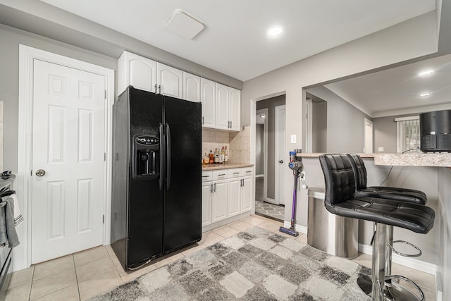 8373 Mckinley, Center Line, MI 48015 - kitchen with black fridge with ice dispenser, white cabinets, decorative backsplash, a kitchen breakfast bar, and light tile patterned floors