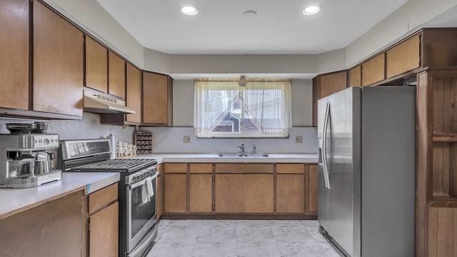 kitchen featuring stainless steel appliances, under cabinet range hood, a sink, light countertops, and brown cabinets