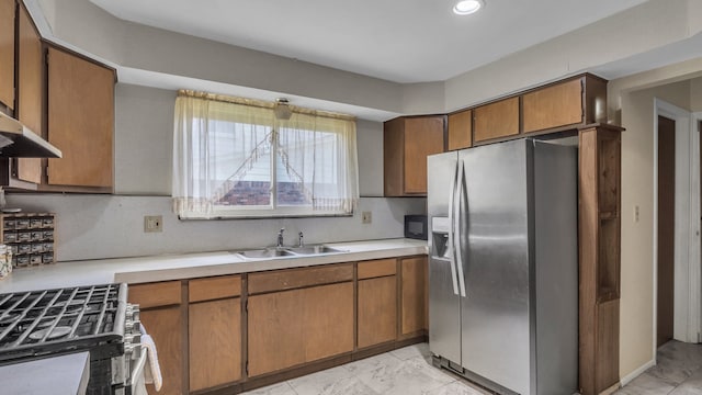 kitchen featuring stainless steel appliances, a sink, light countertops, light marble finish flooring, and recessed lighting