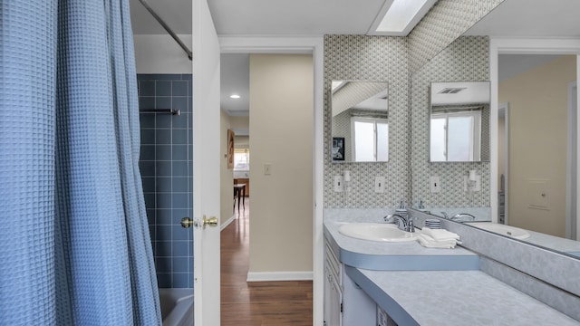 bathroom featuring wood finished floors, baseboards, vanity, and shower / tub combo with curtain