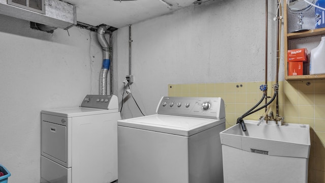 laundry room featuring washing machine and clothes dryer and tile walls